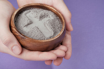 Hands with gray ash cross on purple background. Ash Wednesday