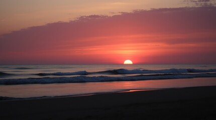 Beautiful orange sunset paints the sky above the ocean as waves crash on the sandy beach