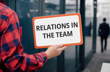 RELATIONS IN THE TEAM words inscription on a sign in the hands of a worker