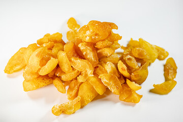 A close-up view of vibrant golden-yellow freeze-dried quince pieces against a white background. The texture and detail of the dried fruit are highlighted.