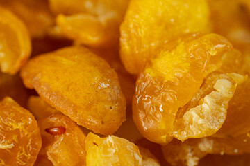 A close-up view of vibrant golden-yellow freeze-dried quince pieces against a white background. The texture and detail of the dried fruit are highlighted.