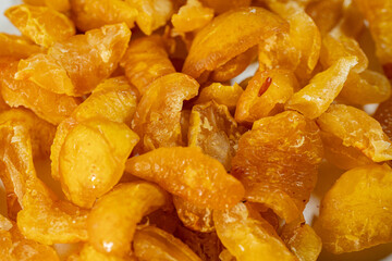 A close-up view of vibrant golden-yellow freeze-dried quince pieces against a white background. The texture and detail of the dried fruit are highlighted.