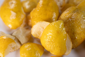 A close-up view of vibrant golden-yellow freeze-dried quince pieces against a white background. The texture and detail of the dried fruit are highlighted.