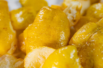 A close-up view of vibrant golden-yellow freeze-dried quince pieces against a white background. The...