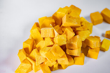 Macro shot of freeze-dried pumpkin cubes showcasing their vibrant orange color and textured surface. Perfect for healthy eating and food preservation themes.