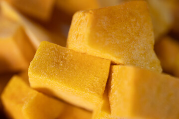 Macro shot of freeze-dried pumpkin cubes showcasing their vibrant orange color and textured surface. Perfect for healthy eating and food preservation themes.
