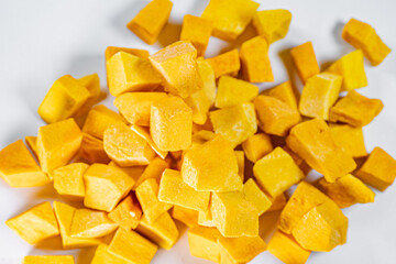 Macro shot of freeze-dried pumpkin cubes showcasing their vibrant orange color and textured surface. Perfect for healthy eating and food preservation themes.