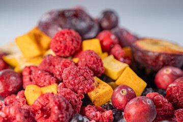 A vibrant mix of freeze-dried blueberries, physalis, cranberries, raspberries, apples, and pumpkin cubes. This colorful assortment showcases a variety of textures and natural colors, perfect for snack