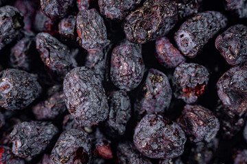 A detailed close-up of freeze-dried honeysuckle berries, showcasing their deep purple hue, wrinkled texture, and natural appeal. Perfect for culinary or snack applications.