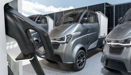 Electric vehicles charging station on a background of a small city delivery trucks