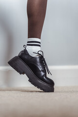 Legs of a young woman wearing loafer boots and funny socks 