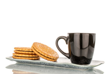 Several sweet delicious cookies on a ceramic saucer with a cup, close-up, isolated on a white background.