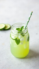 Freshly made green juice with ice cubes, a slice of lime, and mint leaves in a mason jar, suggesting detoxification and health.