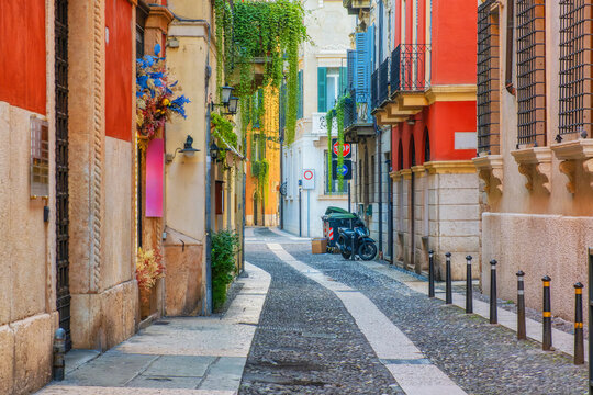 Medieval narrow street with colorful building facades and cobblestone in Verona old town, Veneto, Italy at sunrise. Italian street with nobody. Travel destination in Europe