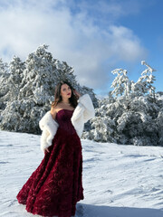 beautiful woman with dark hair in luxurious evening dress with accessories posing in the snowy...