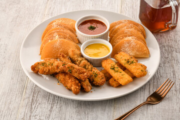 TRIO SNACKS PLATTER with finger food, nuggets, dumpling, momo, mayo and garlic chilli sauce served in dish isolated on wooden table side view of italian fast food