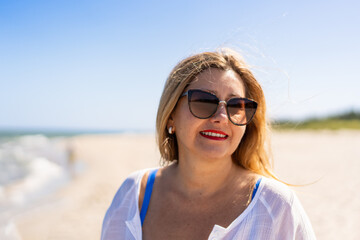 Portrait of beautiful happy middle aged woman against beach background. Pretty smiling female face...