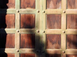 A charming rustic wooden door with textured panels, bathed in light and shadow play, showcasing an...