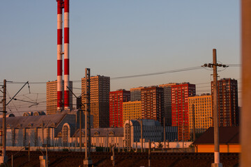 Railway tracks next to houses on the background of sunset. The station and residential high-rise buildings