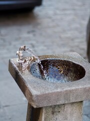 A classic stone fountain with a steady stream of water splashes gently into the basin, surrounded...