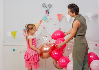 Mom with little girl decorate room for children birthday party