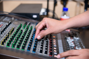 Hands adjusting the knobs and faders on a professional audio mixing console in a studio