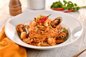 SEAFOOD DIABLO noodles with seashell and red chilli served in dish isolated on wooden table side view of italian fast food