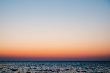 Obraz premium Sunset Gradient: A sky transitioning from deep orange to soft pink, with the horizon fading into a calm, dusky blue