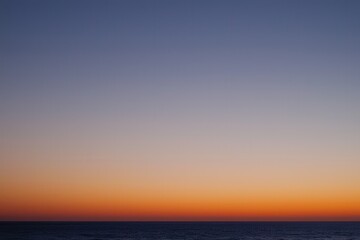 Obraz premium Sunset Gradient: A sky transitioning from deep orange to soft pink, with the horizon fading into a calm, dusky blue