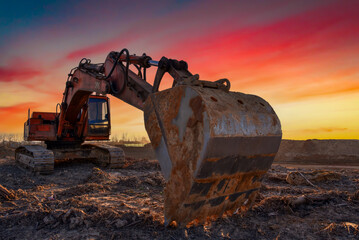 Excavator on sunset. Open-pit mining. Backhoe dig ground in quarry. Heavy construction equipment on...