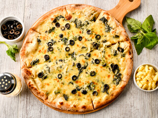 Spinach and Olive Pizza topped with fresh spinach, olives, and melted cheese served on wooden board top view of italian fast food
