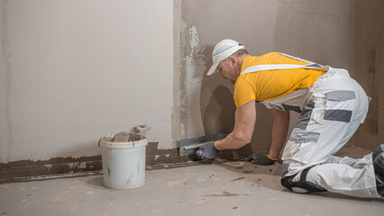 A worker when applies a liquid membrane on the concrete bathroom  floor. Foolproof waterproofing for a tile bathroom.