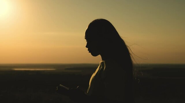 girl prays with bible her hands sunset. young girl asks for help. read prayer dawn. human faith dream. ask sky. relaxation concept. happy person lives faith. good book helps find way. pray park sunset