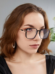 Fototapeta premium A glamorous woman in stylish glasses poses looking at the camera