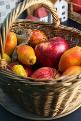 Red apples and yellow pears in a wicker basket on a top of kitchen counter, close up. 
