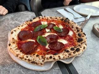 Tasty pepperoni pizza with basil served at restaurant