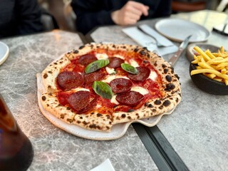 Tasty pepperoni pizza with basil served at restaurant