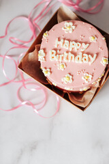 Pink Bento birthday cake decorated with daisies. In a small box with a pink ribbon