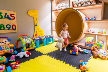 Young child playing in vibrant daycare play area filled with educational toys and activities