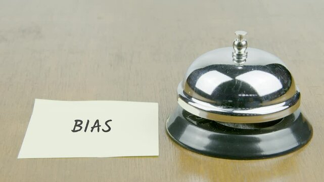 Finger Index Ringing Bell with Bias Text or Word on Yellow Note Paper on Desk or Table