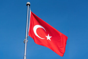 Turkish flag against blue sky.