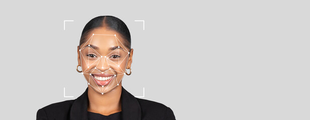 Subject demonstrates facial recognition technology with a joyful expression. The background is gray and empty, emphasizing the person and features of the identification technology.