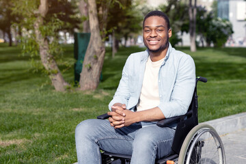 Fototapeta premium Accessible environment for disabled people concept. Happy black guy in wheelchair going down ramp on city street, using impaired-friendly facilities outdoors. Full length