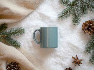 Cozy winter setup with a teal mug surrounded by pine branches and pinecones on a soft blanket,...