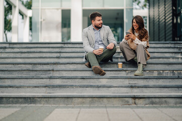 Business people having coffee break using smartphone on stairs