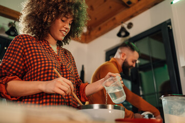 Couple cooking together adding water to bowl in kitchen at home
