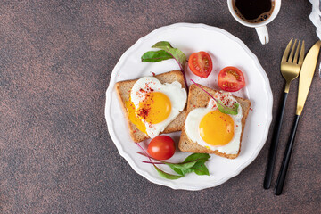 Heart-shaped fried eggs on toast with cherry tomatoes and cup of coffee for breakfast, Top view