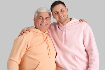 Young man with his father hugging on light background