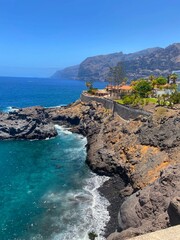 Villas on the cliffs above the Atlantic Ocean. Waves and the shore in a sunny weather.
