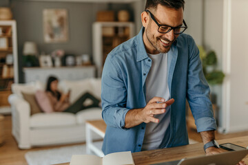 Caucasian man calculating expenses at a table with a laptop and documents in a cozy, contemporary space